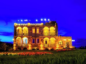 A stone building with multiple arched windows and a balcony, illuminated by warm lights. - Ala Stone Hotel (Nevsehir)