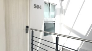Un interior moderno con una puerta marcada '504', una barandilla de metal y una habitación luminosa e iluminada por el sol.