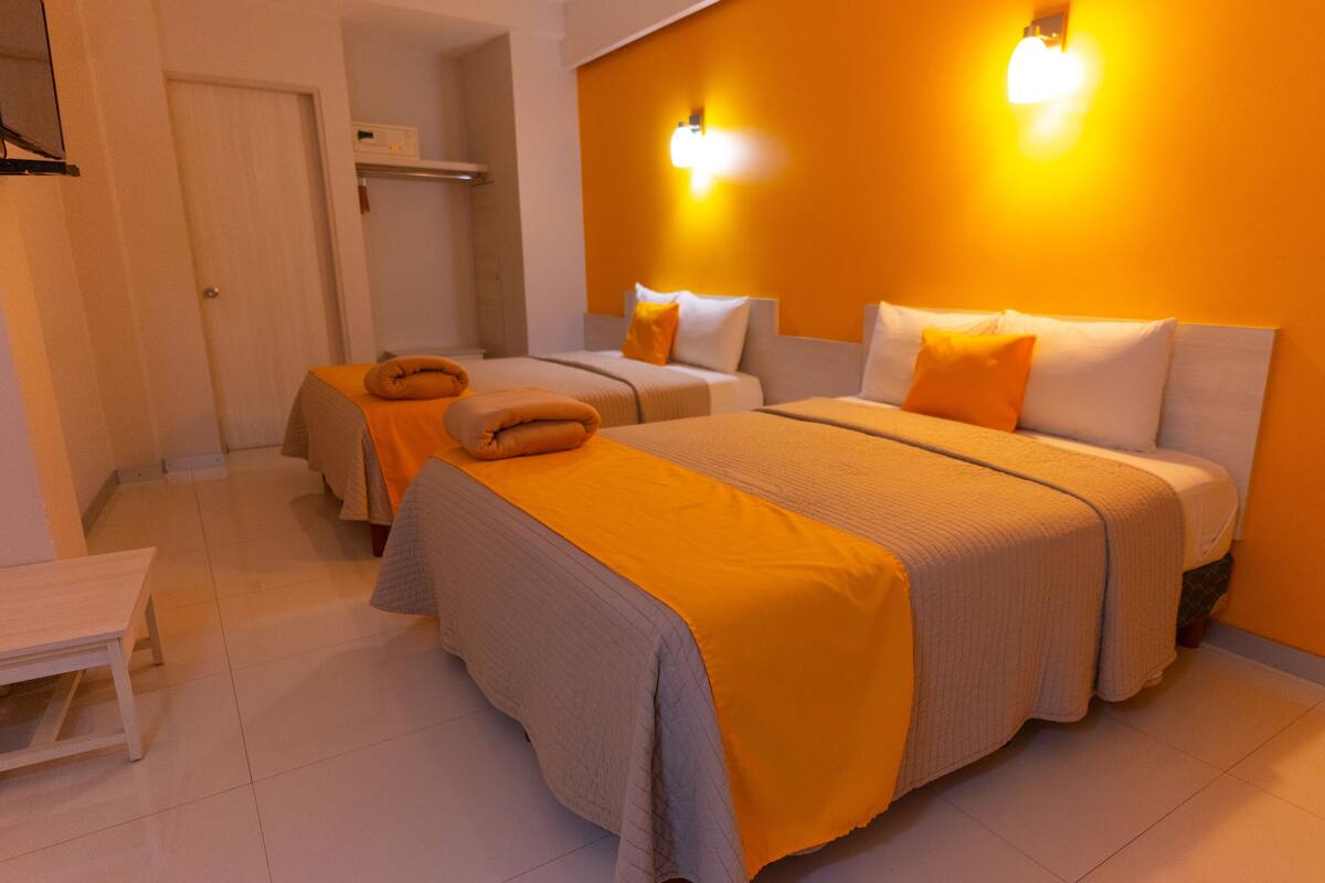 Habitación de hotel con dos camas, una mesita y un armario.