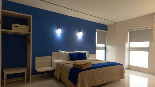 Un dormitorio moderno con una cama grande, una mesita de noche, un banco y un armario.