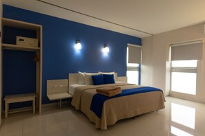Un dormitorio moderno con una cama grande, una mesita de noche, un banco y un armario.