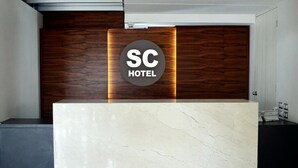 Un mostrador de recepción de hotel con encimera de mármol y un panel de madera al fondo.