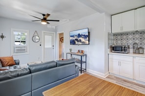 Un salon moderne avec un canapé gris, une table basse en bois et un ventilateur de plafond.