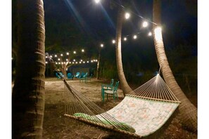Relax in a hammock suspended between palm trees, surrounded by comfortable seating and a serene atmosphere.