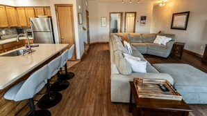 Eine moderne Küche mit einem Edelstahlkühlschrank, Holzschränken und einer Bar mit Hockern.