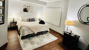 Ein Schlafzimmer mit einem Bett, einem Deckenventilator, einem Nachttisch mit Lampe, einem Spiegel und einem Teppich.
