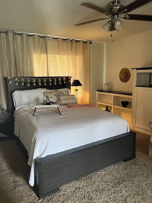 Una camera da letto con un letto, comodini, un ripiano e una ventola a soffitto.