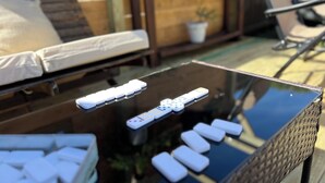 A glass-top table with dominoes and a remote control. - The Sunrise House (Port Richey)