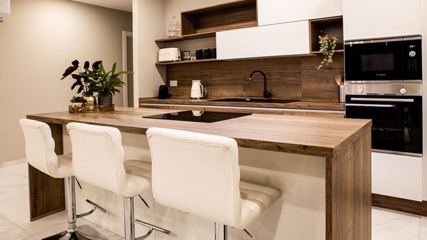A modern kitchen with a central island, bar stools, a Bosch microwave, and a sink.