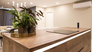 A modern kitchen with a wooden countertop, a black cutting board, and a potted plant.