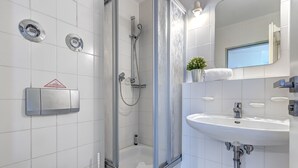 Een moderne badkamer met een douchecabine van glas, een wit wastafelmeubel en een toilet.