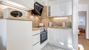 Een moderne keuken met witte kasten, een magnetron, een oven en een spoelbak.
