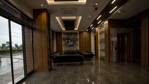 A modern lobby with a marble floor, leather seating, and a large glass wall. - Gursoy Exclusive Hotel (Arsin)