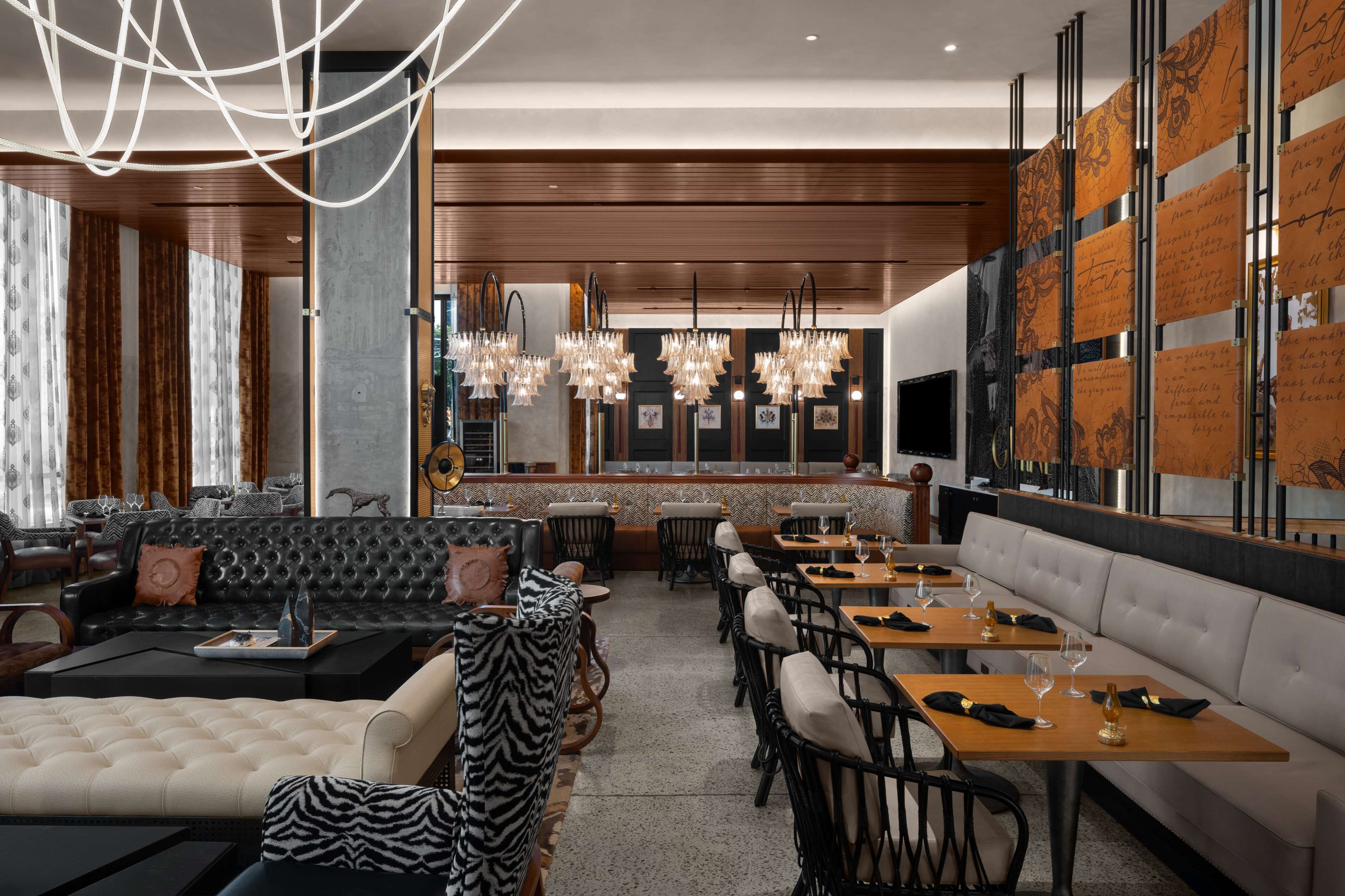 Un ristorante moderno con zona bar, sedute in pelle e una parete ampia con pannelli decorativi.