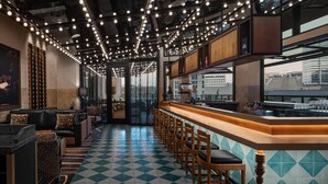 Een bar met een zwart-wit schaakbordvloer, barstoelen en een lange toonbank.