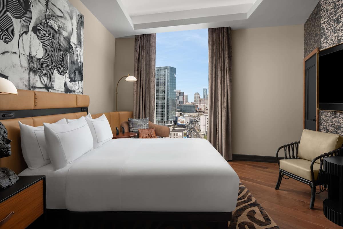 Een hotelkamer met een groot bed, uitzicht op de stad, een televisie en een stoel.
