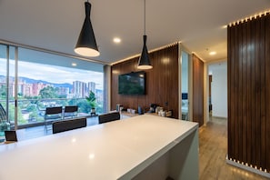 Enjoy meals and casual gatherings in this kitchen with a large island, pendant lights, and a flat-screen TV.