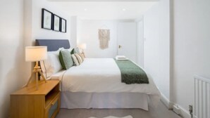 A bedroom with a bed, bedside tables, a lamp, and a wall-mounted picture frame.