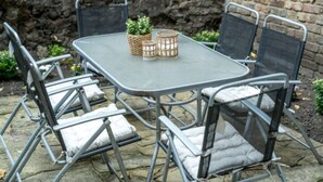 A metal table with four chairs, a small potted plant, and two candle holders.