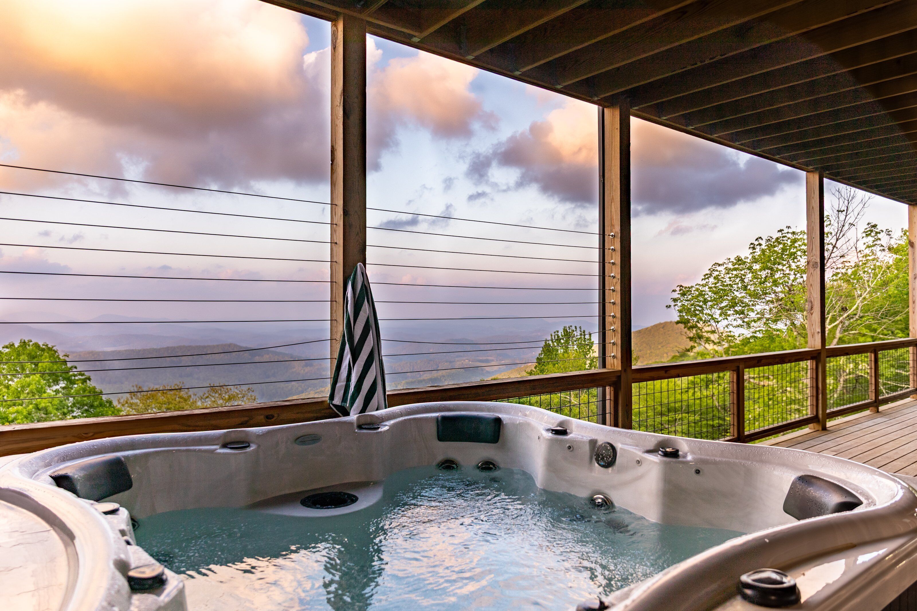 Uma banheira de hidromassagem com deck de madeira e grandes janelas com vista para uma paisagem deslumbrante.