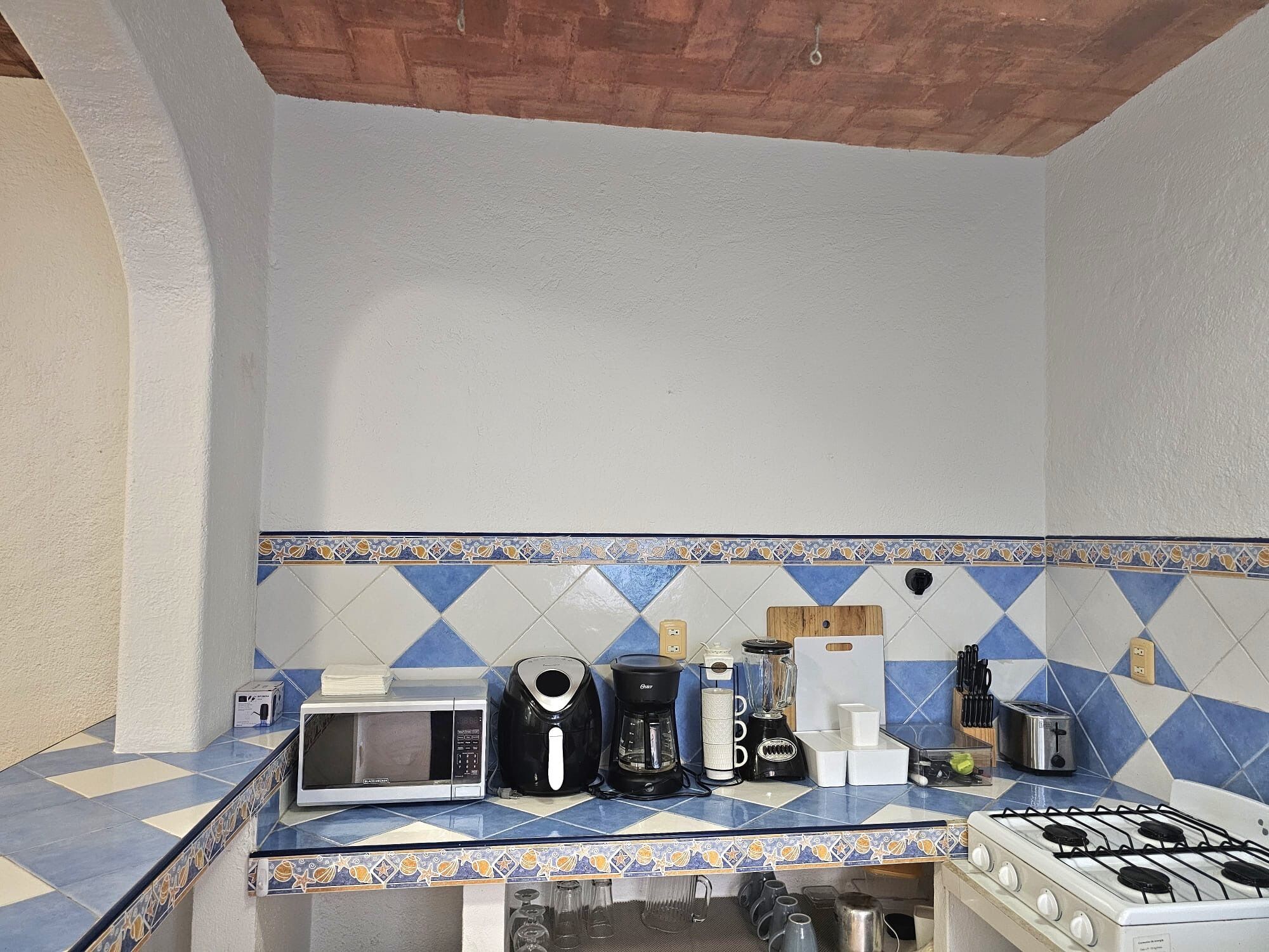 A kitchen with a microwave, coffee maker, toaster, and gas stove.