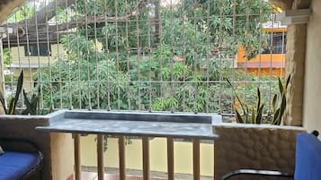 Une terrasse avec une table et deux coins salons bleus dotés de coussins, entourée d’un mur en pierre et d’une rambarde en métal.
