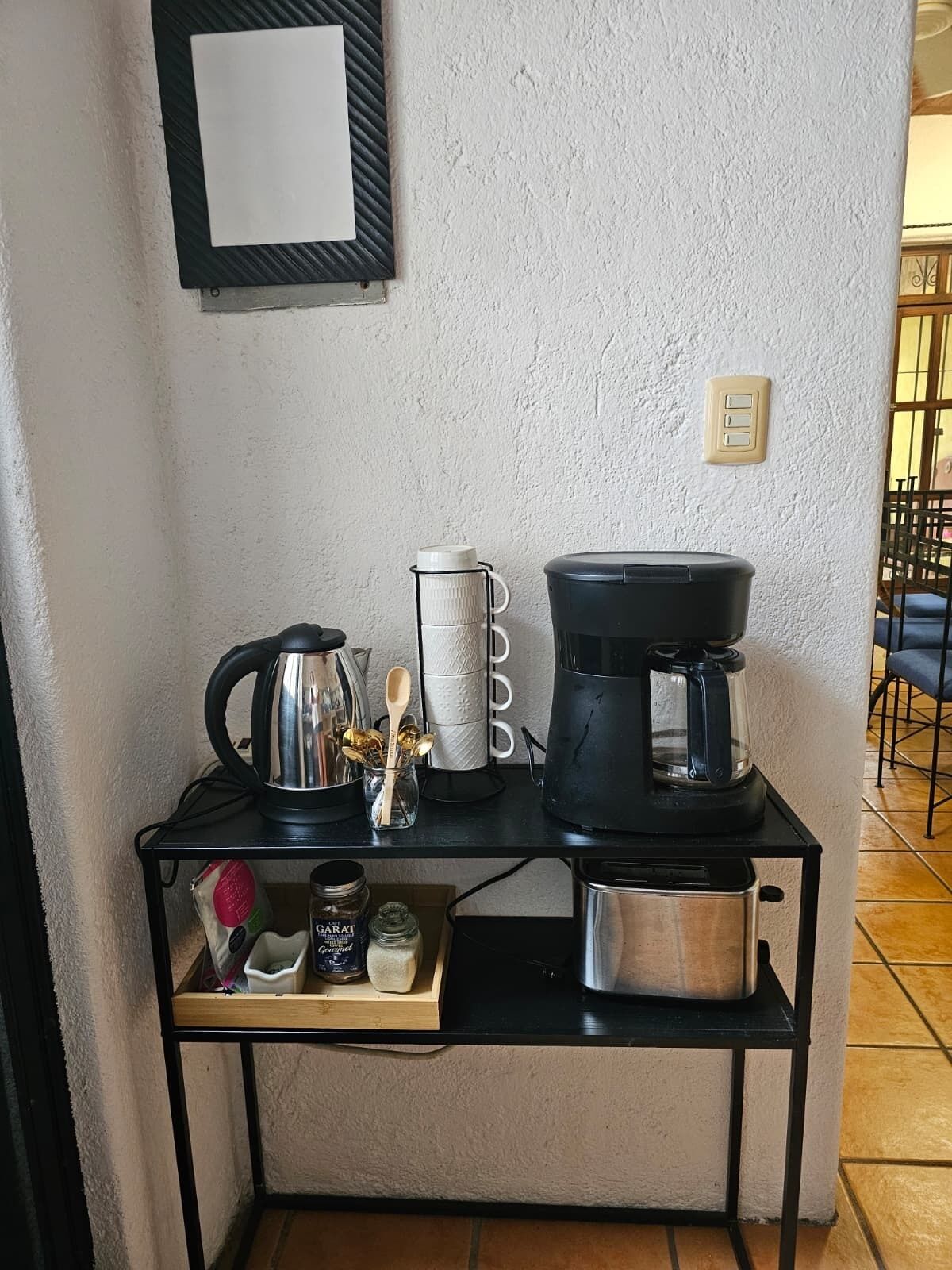 A kitchen counter with a coffee maker, a kettle, a jar of sugar, and a small container of spices.