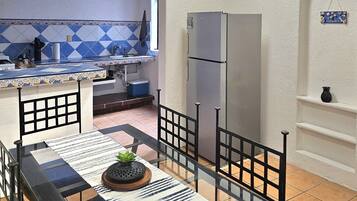 A kitchen with a tiled backsplash, a refrigerator, and a dining area with a table and chairs.