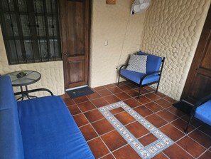 A room with a blue sofa, a patterned rug, a wooden door, and a small table with a plant.