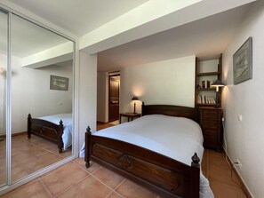 Une chambre à coucher avec un grand miroir, un lit en bois, une table de chevet avec une lampe et une bibliothèque.