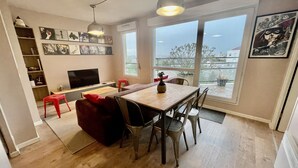 A modern living room with a wooden dining table, red sofa, and a TV on a stand. - Apartment 2 people Toison d'Or district (Dijon)