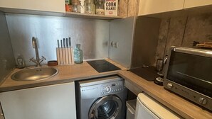 A compact kitchen with a washing machine, a microwave, and a sink. - Apartment 2 people Toison d'Or district (Dijon)