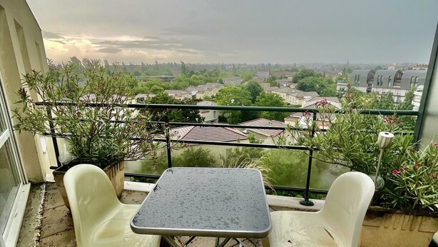 A balcony with a table and two chairs, overlooking a cityscape. - Apartment 2 people Toison d'Or district (Dijon)