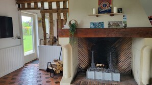 Un intérieur rustique avec une cheminée, des poutres en bois et un sol carrelé.