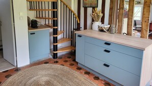 Un escalier avec des marches en bois et des rampes noires, une commode bleu clair avec des tiroirs, un tapis tissé et une affiche accrochée au mur.
