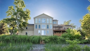 A two-story residential building with a flat roof, multiple windows, and a visible garage. - 200' of private waterfront, hot tub & kayaks (Cayuga)