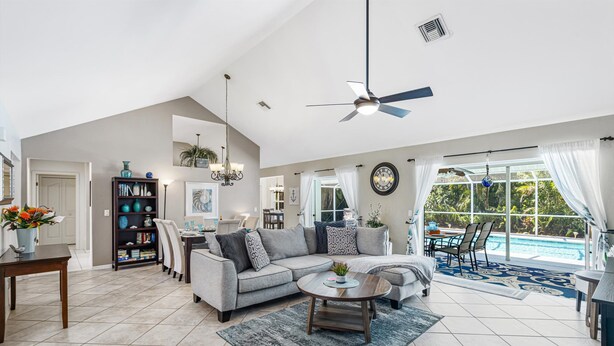 A spacious living room with a gray sectional sofa, a coffee table, and a dining area with a chandelier.