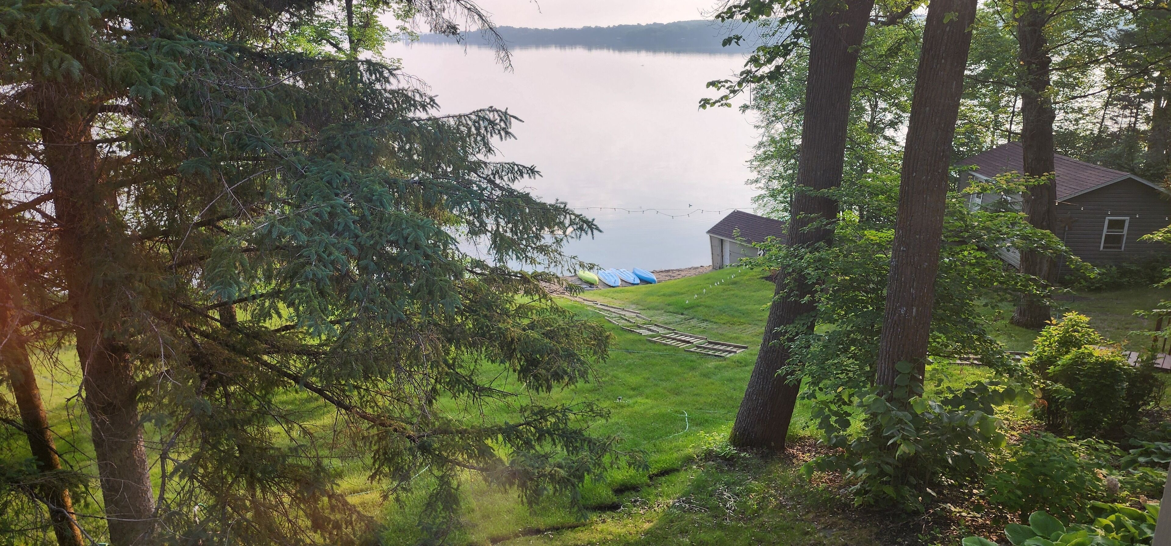 Ein Haus am See mit Rasen, Bäumen und einer kleinen Baugrundstück.