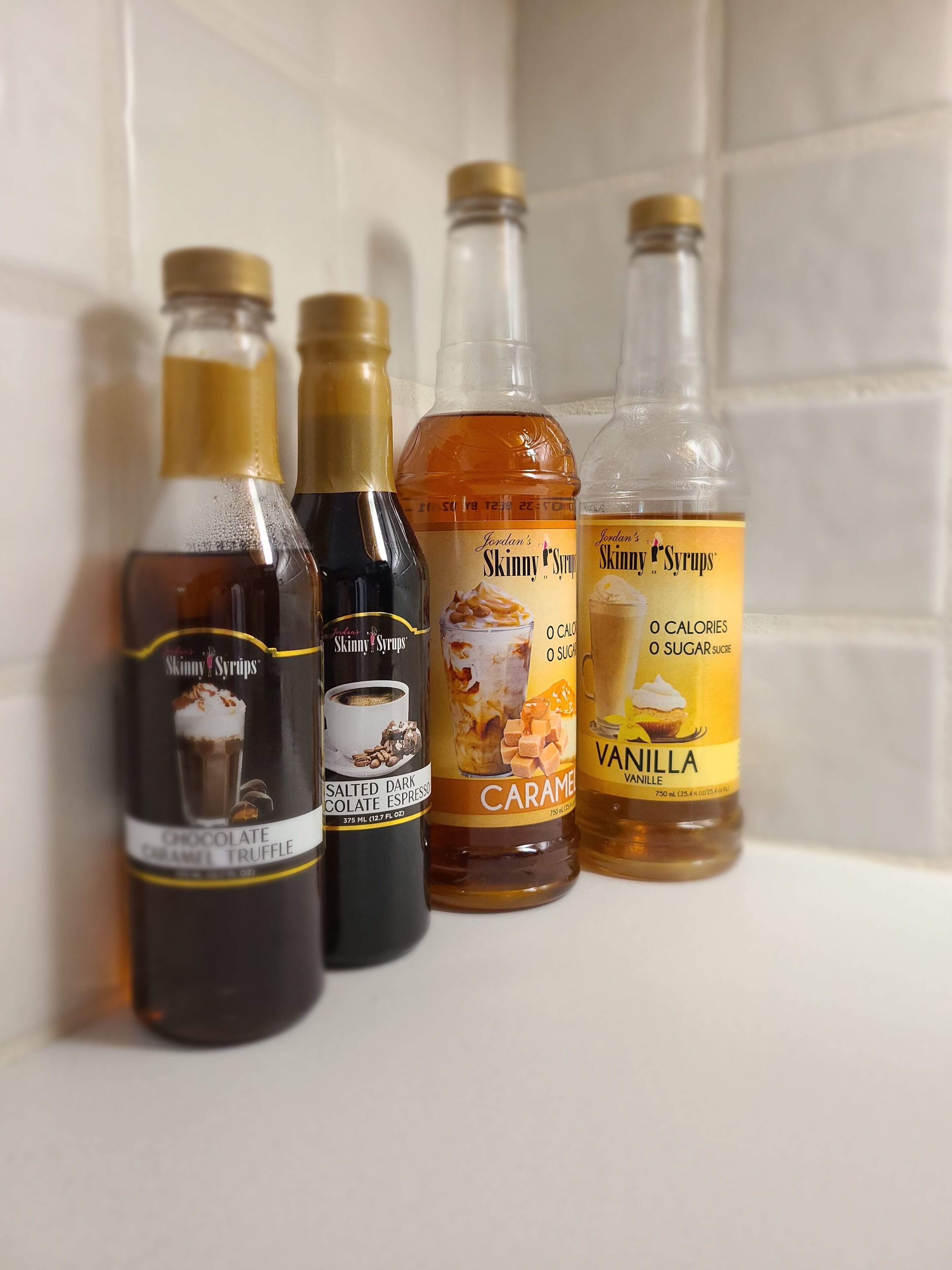 Quatre bouteilles de sirop sur une étagère.