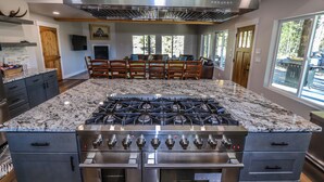 Una cocina con una isla grande, electrodomésticos de acero inoxidable y un comedor con sillas de madera y un sofá.