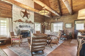 A rustic cabin interior with a stone fireplace, wooden furniture, and a star decoration on the wall.