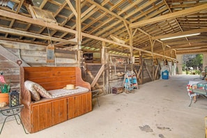 Interior rústico de un granero con un banco de madera, una mesa y una lámpara colgante.