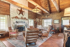 A rustic interior with a fireplace, wooden furniture, and a star decoration on the wall. - Doe Creek Ranch | 2BR Cabin with Horse Amenities (Bandera)