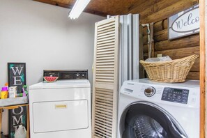 A laundry room with a washing machine, dryer, and a 'Welcome' sign.