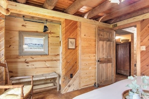 Ein Holzblockhaus-Innenraum mit einer Bank, einem gerahmten Bild und einer Tür.