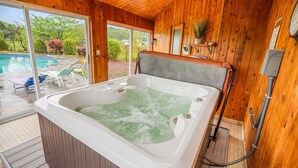 A wooden cabin with a hot tub, a sliding glass door to a backyard, and a small shelf with a plant. - Beautiful modern villa with pool suana hot tub... (Clintondale)