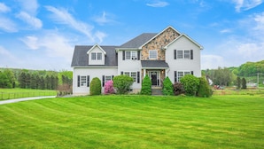 A two-story house with a stone facade, a front porch, and a well-maintained lawn. - Beautiful modern villa with pool suana hot tub... (Clintondale)
