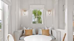 A white paneled room with a round table and two wicker chairs. - “The Ibis” (3025 Southerly Way) 2 person creekside bungalow at Kiawah River ~ Tesla Charger (Johns Island)