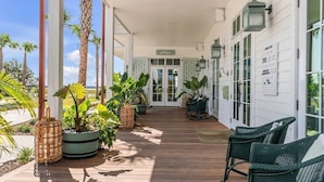 A covered porch with wooden flooring, potted plants, wicker chairs, and a sign reading "Welcome". - “The Ibis” (3025 Southerly Way) 2 person creekside bungalow at Kiawah River ~ Tesla Charger (Johns Island)