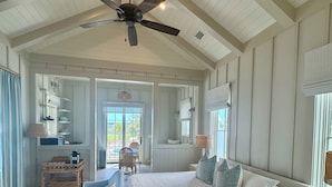 Une chambre spacieuse avec un grand lit, un ventilateur de plafond et une vue sur l’extérieur.